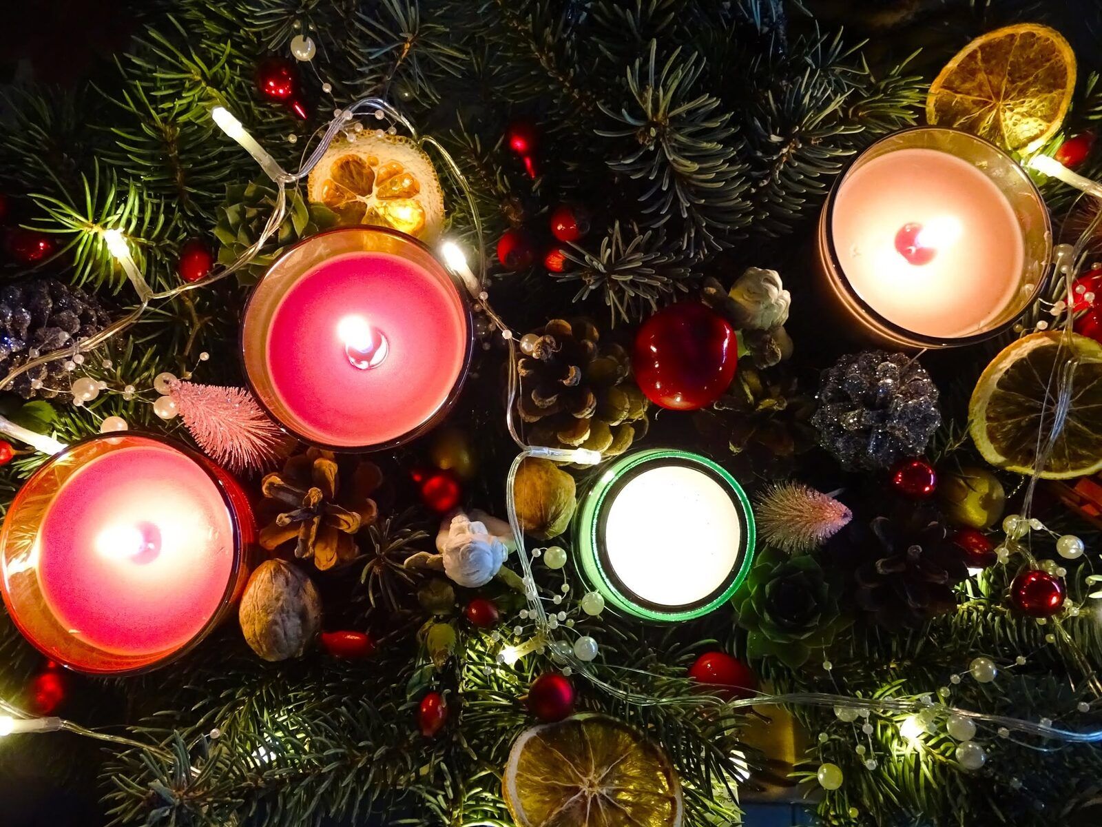 Candles among fir sprigs, cones, dried oranges and lights